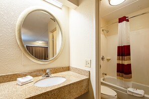 A bathroom with a sink, mirror, and shower. - Red Roof Inn Johnson City (Johnson City)