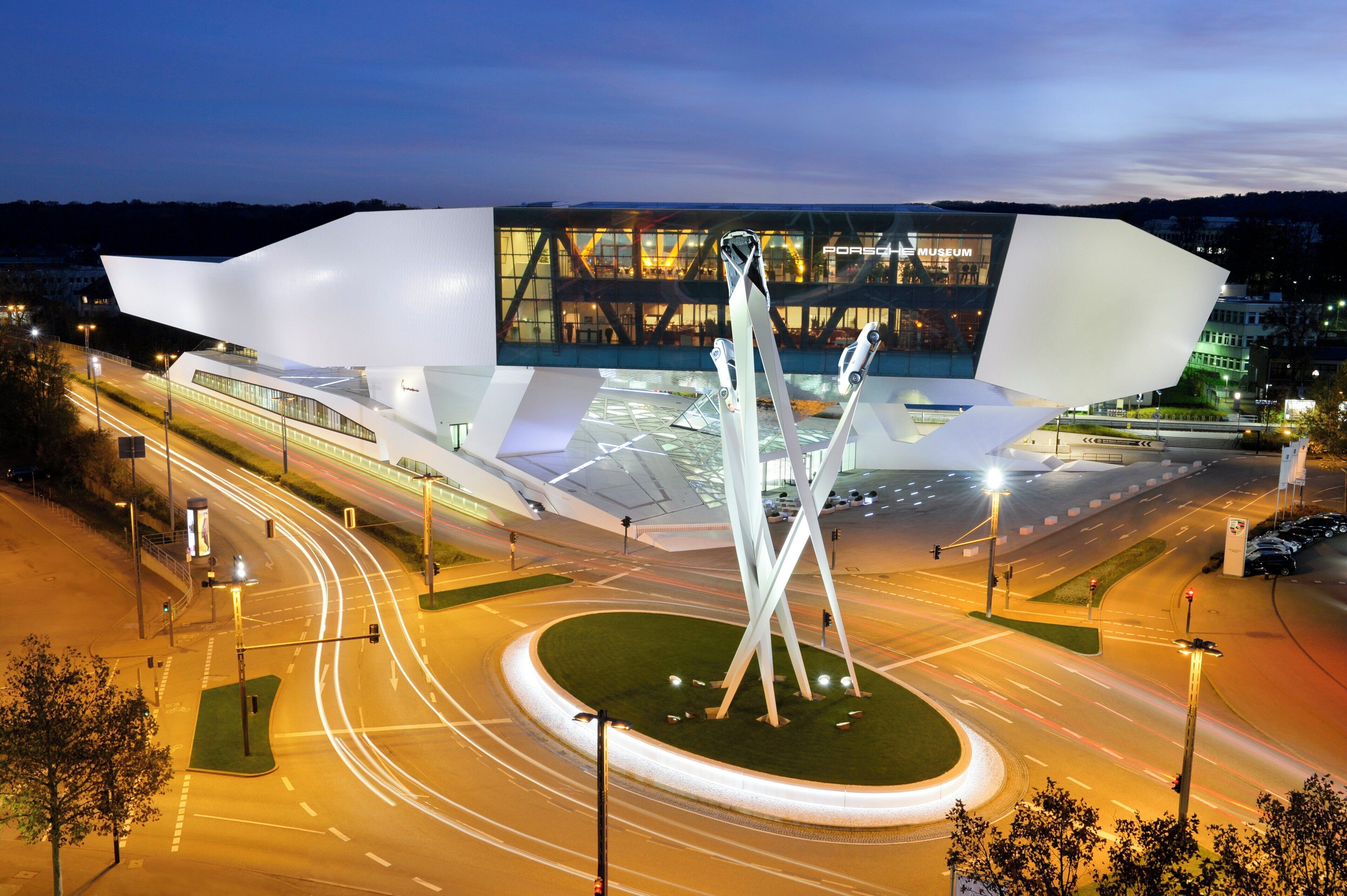 A modern building with a unique architectural design, featuring a central sculpture and a surrounding road with traffic lights.