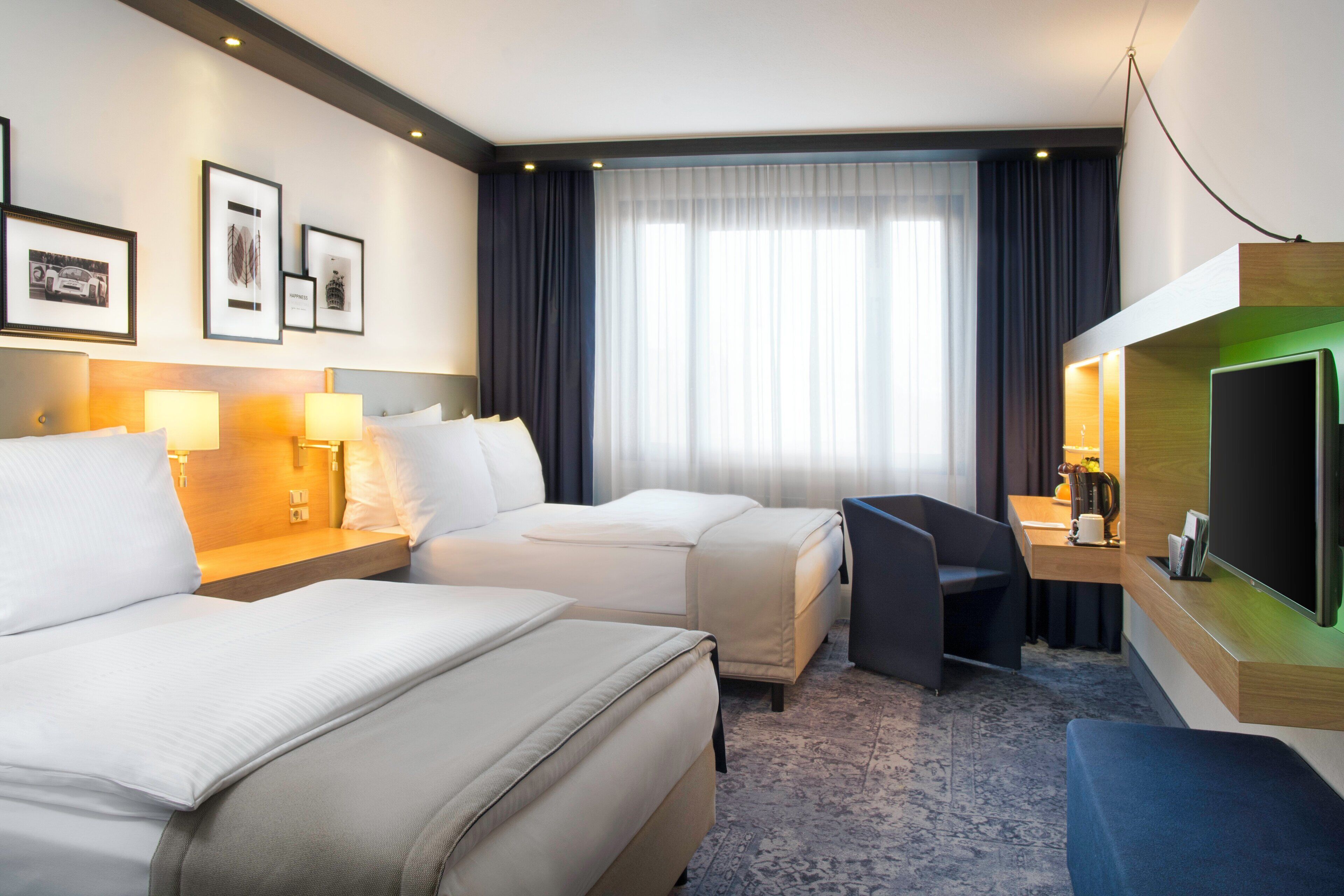A hotel room with two beds, a desk, a TV, and a coffee maker.