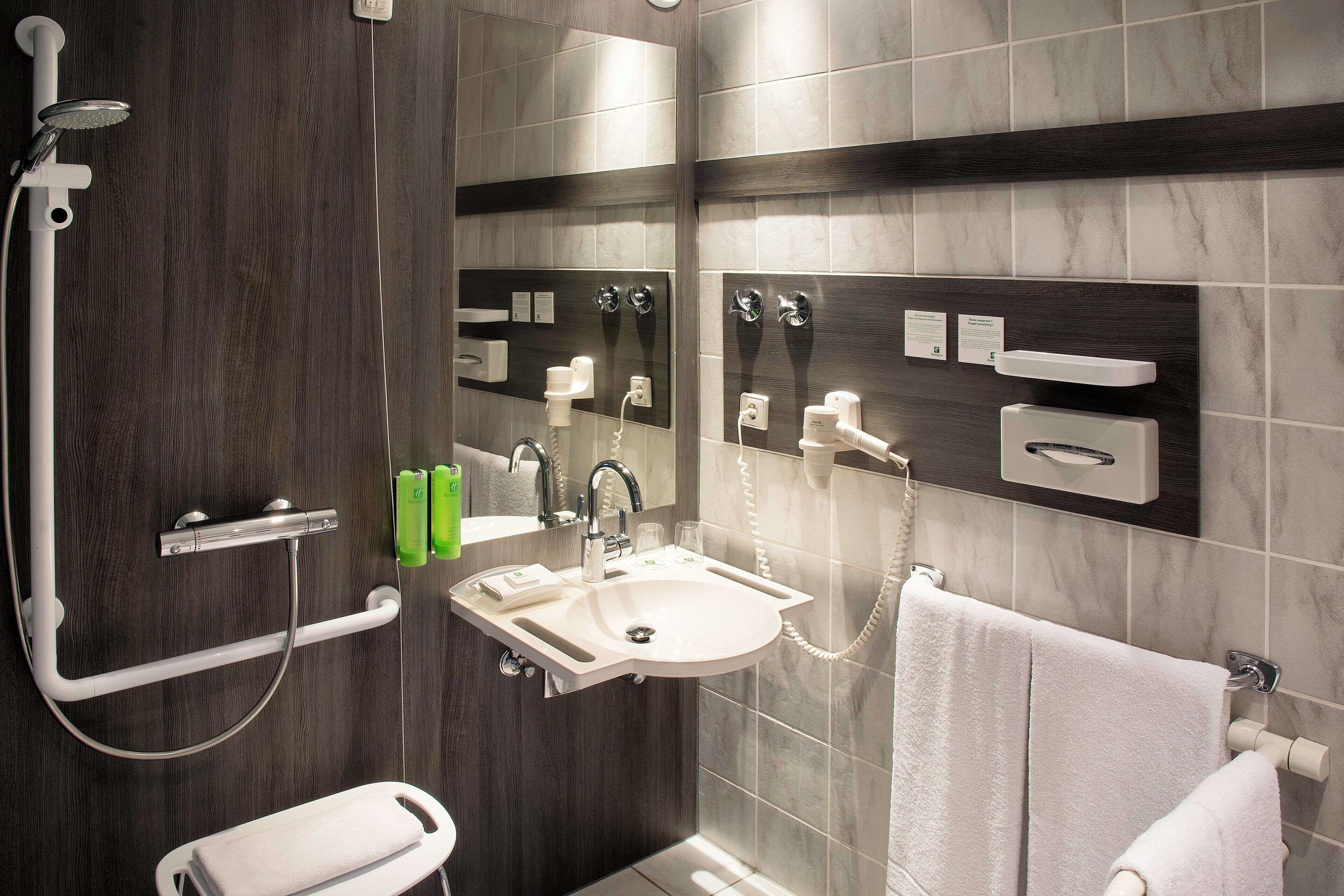A modern bathroom with a shower, sink, and towel rack.