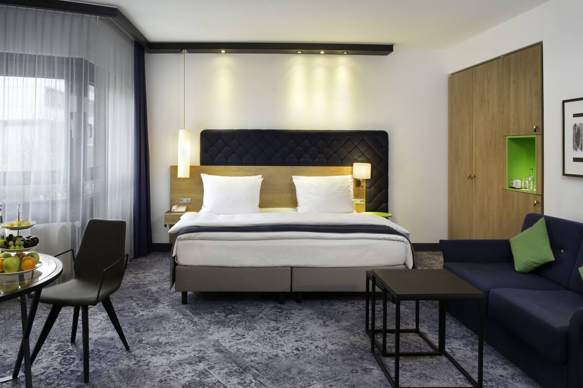 A hotel room with a bed, a sofa, a small table, and a chair.