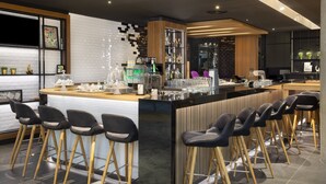 A modern bar area with a counter, stools, and a variety of bar tools. - Holiday Inn Stuttgart by IHG (Stuttgart)