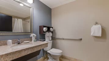 A bathroom with a granite countertop, a white toilet, a towel rack, and a mirror.