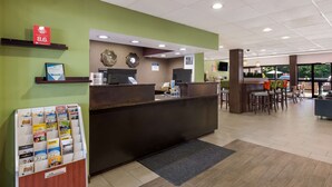 A reception area with a counter, a digital screen, and a seating area with tables and chairs. - Best Western Albemarle Inn (Albemarle)