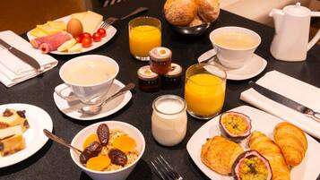 Una mesa de desayuno con diversas opciones de comida, como pasteles, frutas y bebidas.