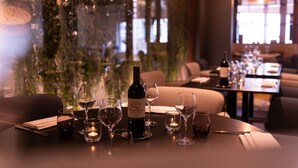 A restaurant table set with wine glasses, a bottle of wine, and a candle. - Hôtel l'Amirauté (Brest)