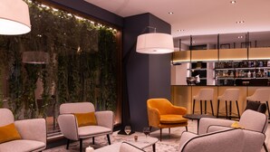 A modern bar area with seating, a bar counter, and a wall with greenery. - Hôtel l'Amirauté (Brest)