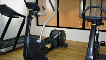 Tres bicicletas estáticas en una habitación con suelo de madera y ventanas amplias.