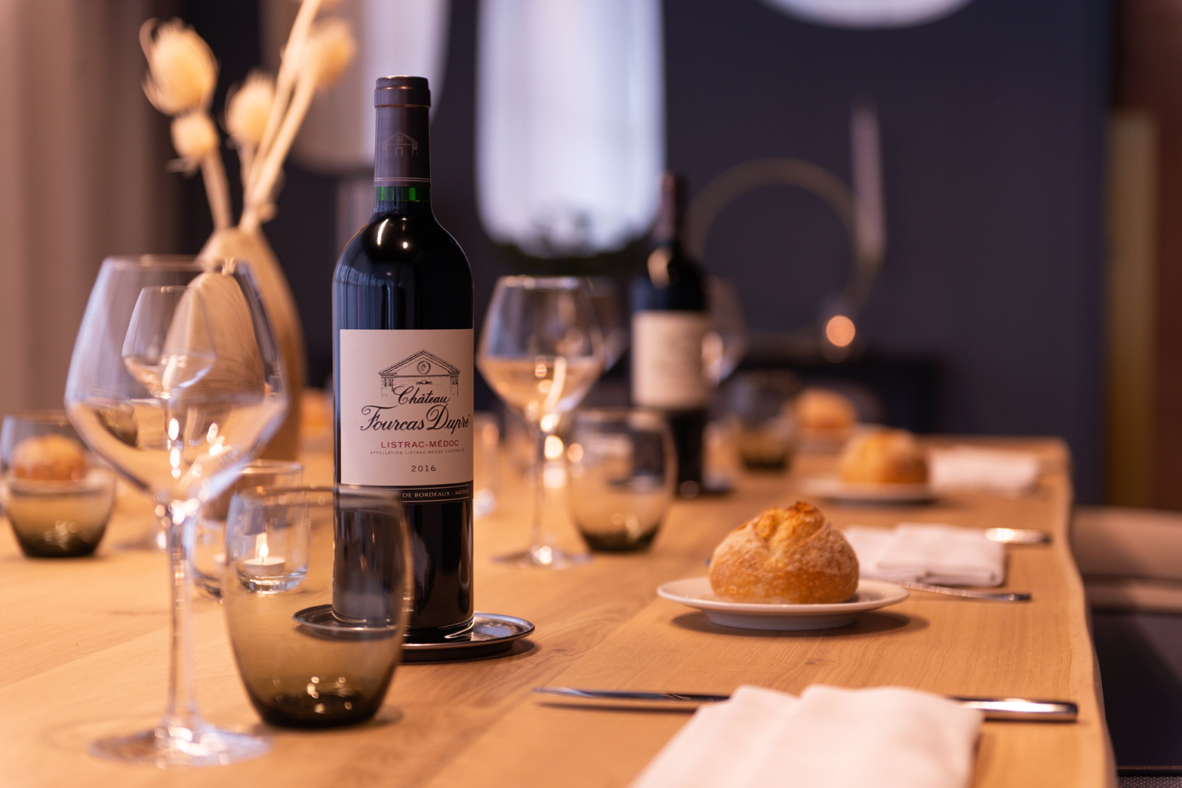 A table set with wine glasses, a bottle of wine, and pastries.