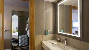 A modern bathroom with a large mirror, a sink, and a shower area.