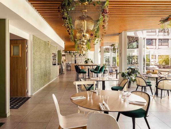 A modern restaurant with a long corridor, dining tables, and chairs.