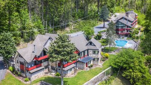A modern two-story house with a stone facade, a swimming pool, and a well-maintained lawn. - Chalet Inn (Gatlinburg)