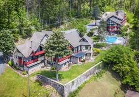 Una casa moderna de dos pisos con fachada de piedra, piscina y césped cuidado.
