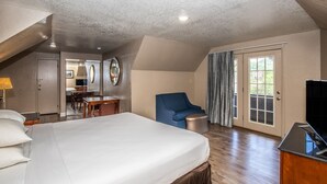 A hotel room with a large bed, a desk, a chair, and a television. - Chalet Inn (Gatlinburg)