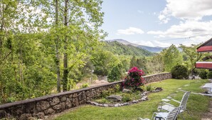 A stone wall with a garden, a bench, and a view of mountains. - Chalet Inn (Gatlinburg)