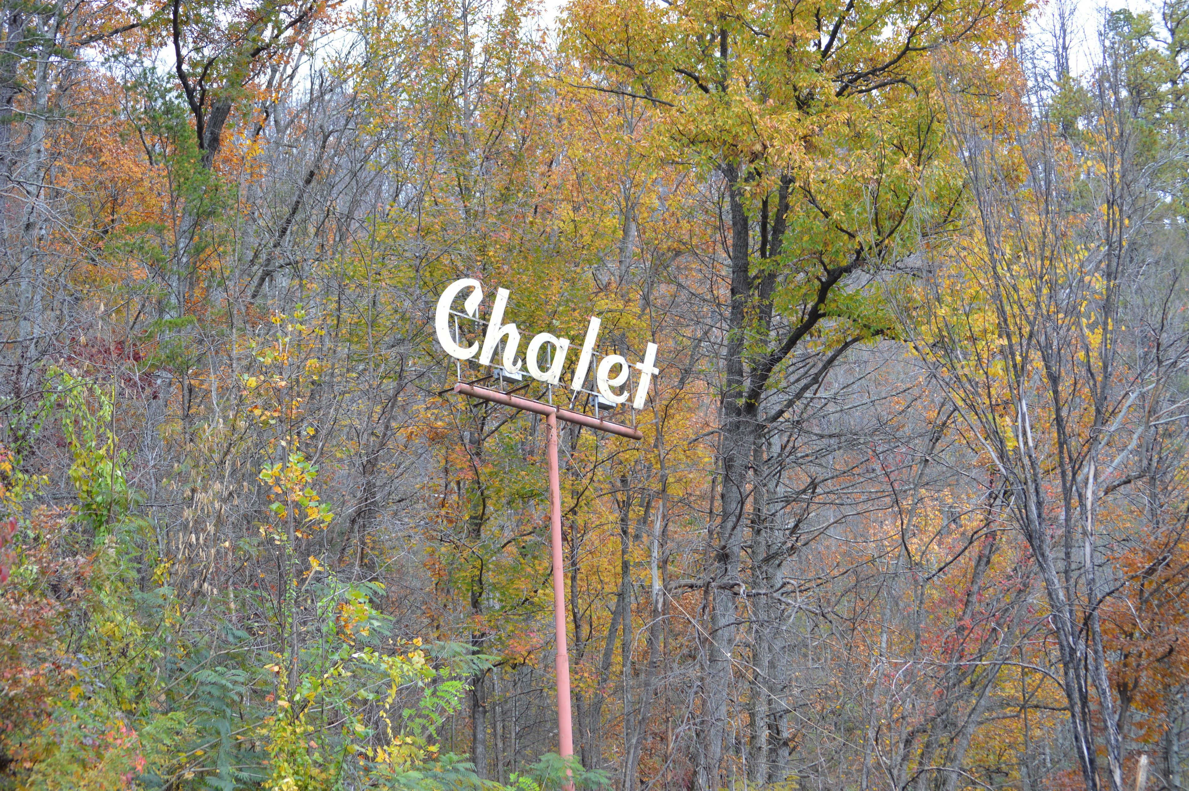 A sign labeled "Chalet" amidst a forested area.