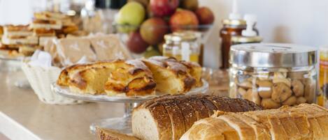 A buffet table with various breads, pastries, and fruits.