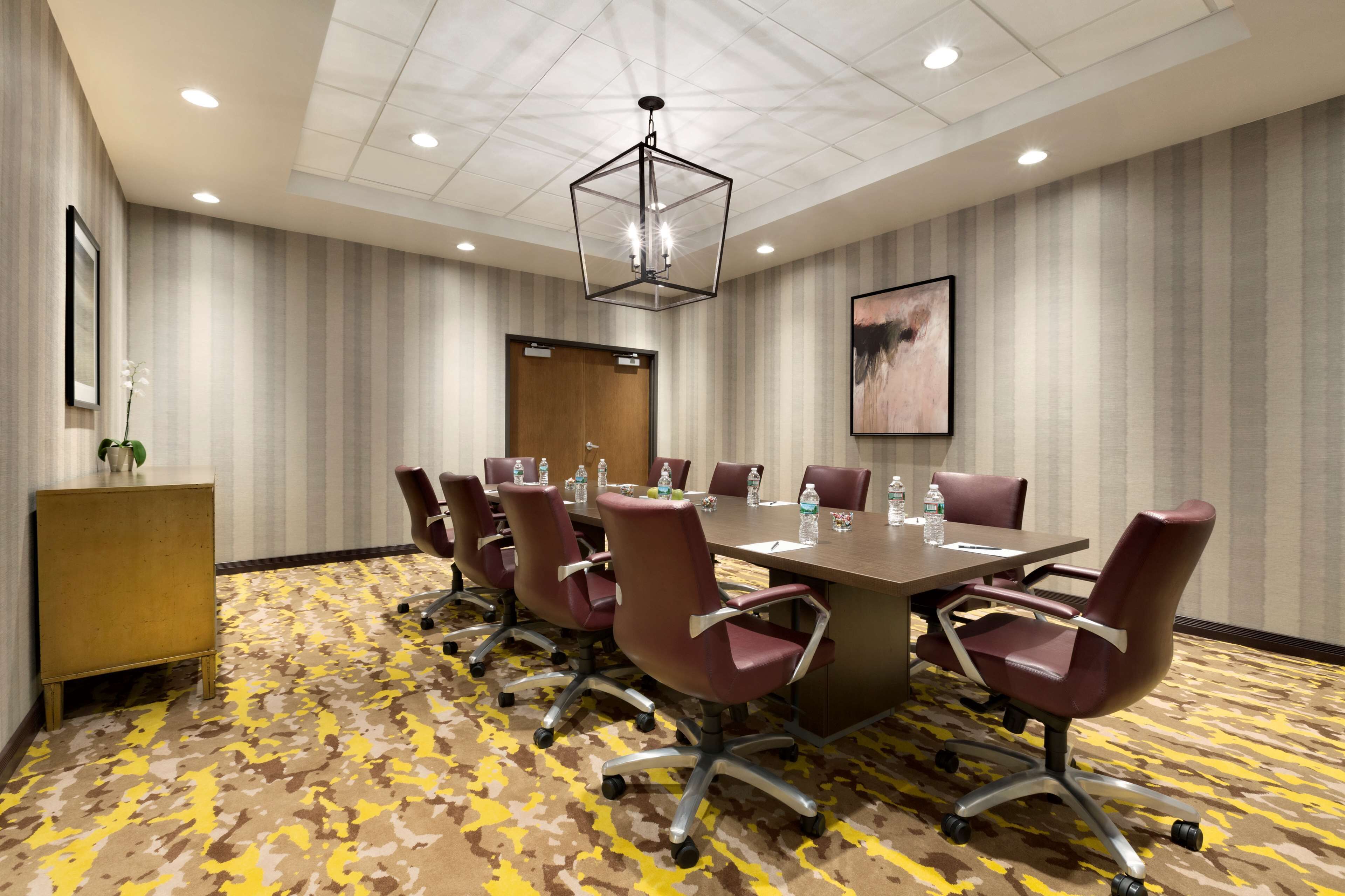 A conference room with a large table, six chairs, a podium, and a ceiling light fixture.