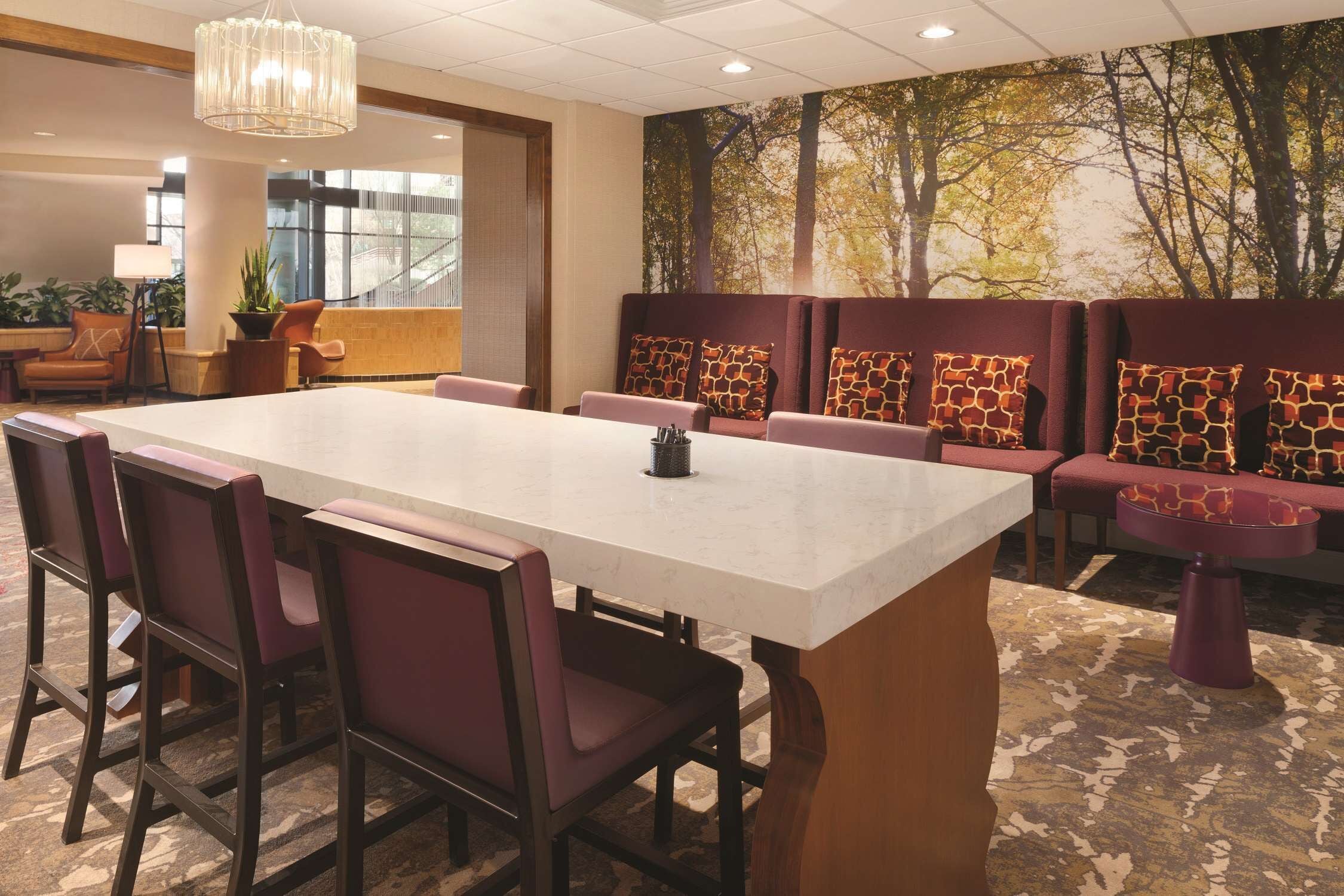 Una sala de conferencias con una gran mesa rectangular, sillas de respaldo alto y un sofá con cojines estampados.