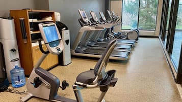 Un gimnasio con cintas de correr, elípticas y un dispensador de agua.