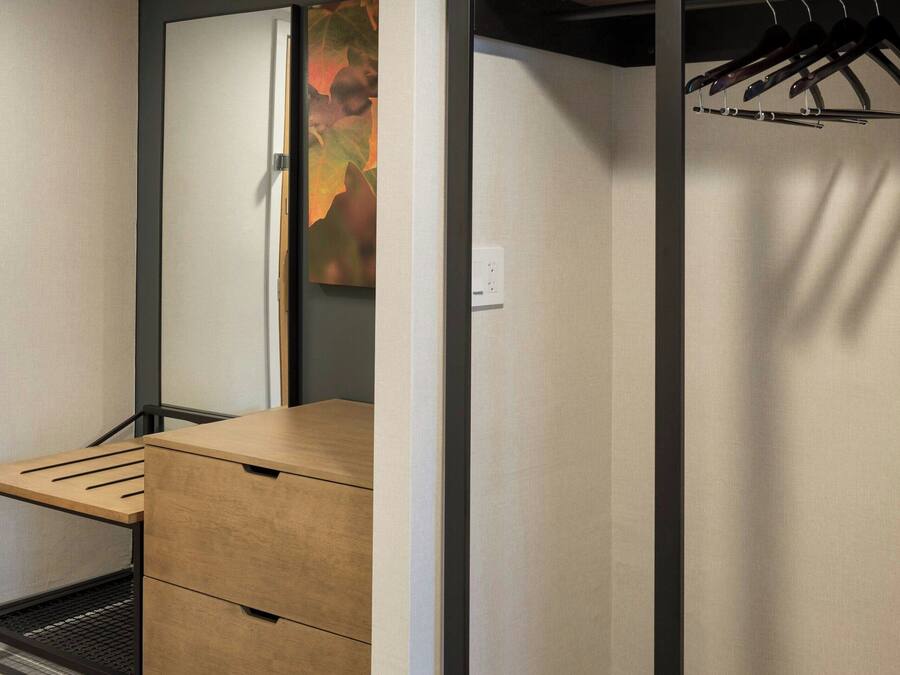 A compact room with a built-in desk, a wardrobe, and a hanging closet.