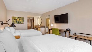 Une chambre d’hôtel avec deux lits, un bureau, une chaise, une télévision, un miroir et un tableau au mur.