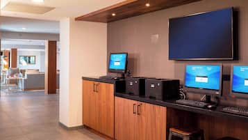 A modern reception area with a wooden counter, three computer monitors, and a flat-screen TV.