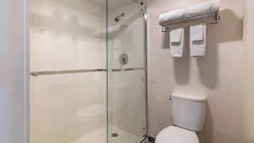 A modern bathroom with a glass-enclosed shower, a white toilet, and a towel rack with three towels.