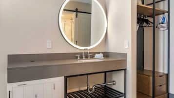A bathroom with a round mirror, a sink, and a towel rack.