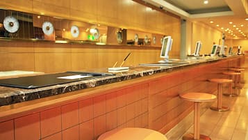A hotel reception area with a marble counter, multiple clocks, and a row of stools.