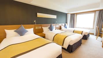 A hotel room with three beds, a large window, and a modern design.