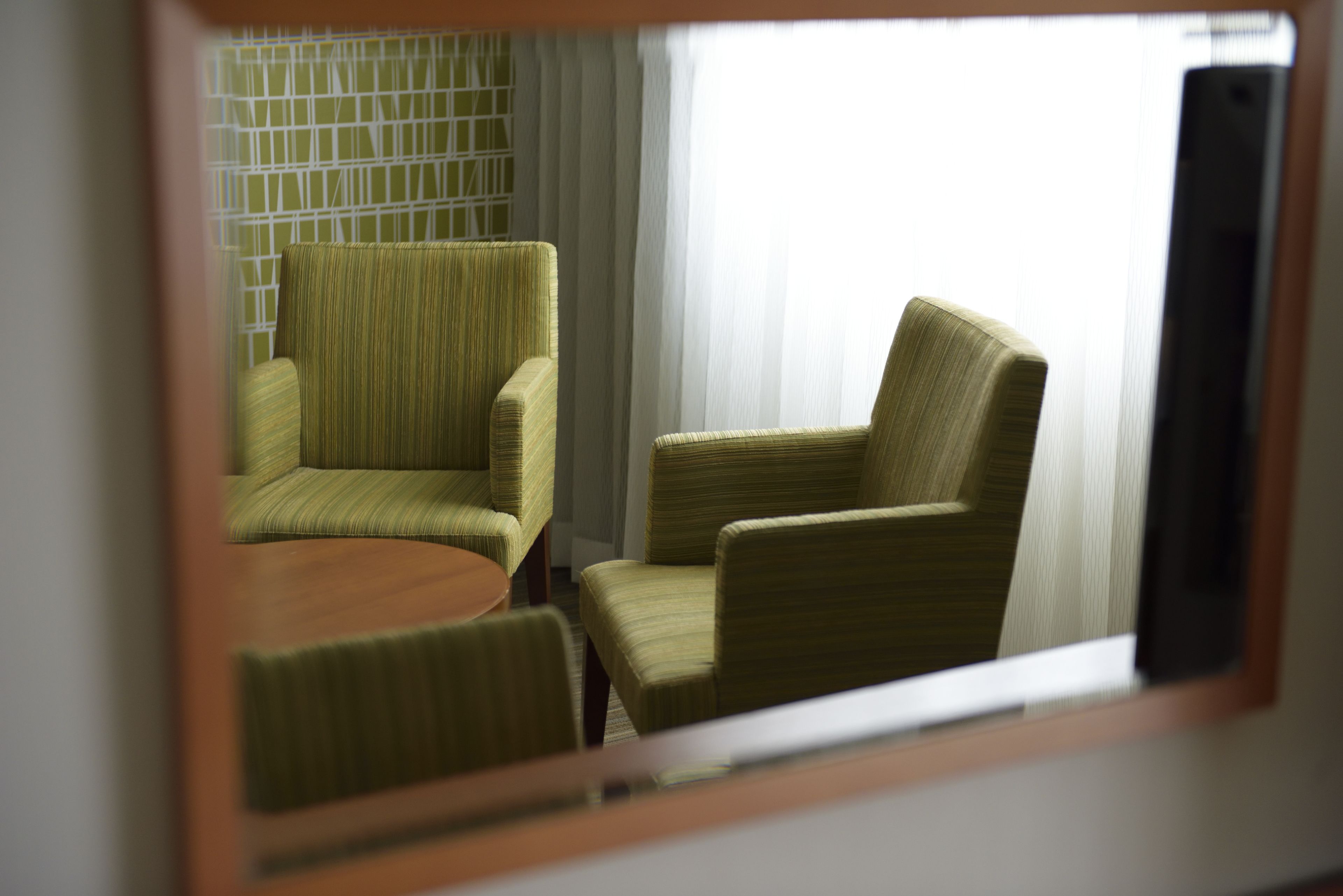 Une pièce comprenant deux fauteuils verts et une petite table ronde.
