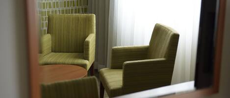 Una habitación con dos sillones tapizados de verde y una pequeña mesa redonda.