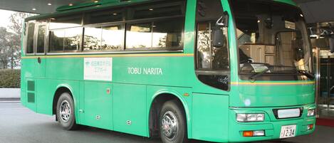 Un autobús verde con la inscripción "TORI NARITA" estacionado en una estación.