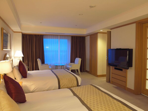 Habitación de hotel con dos camas, televisión, escritorio y una silla.