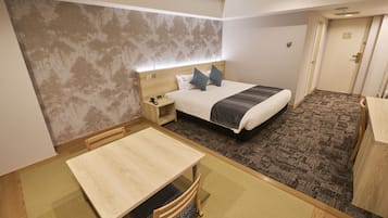 A hotel room with a bed, bedside table, and a small table with chairs.