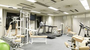 A gym with various exercise machines, treadmills, and a mirrored wall.