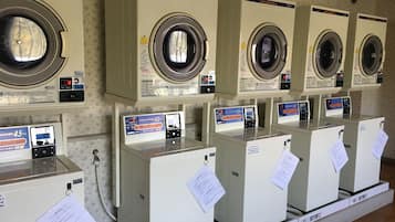 A row of identical washing machines with control panels and price tags.