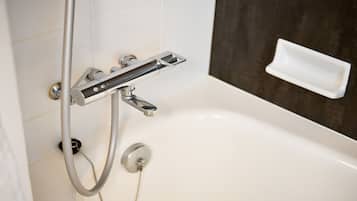 A modern bathroom with a bathtub, a handheld showerhead, and a wall-mounted soap dish.