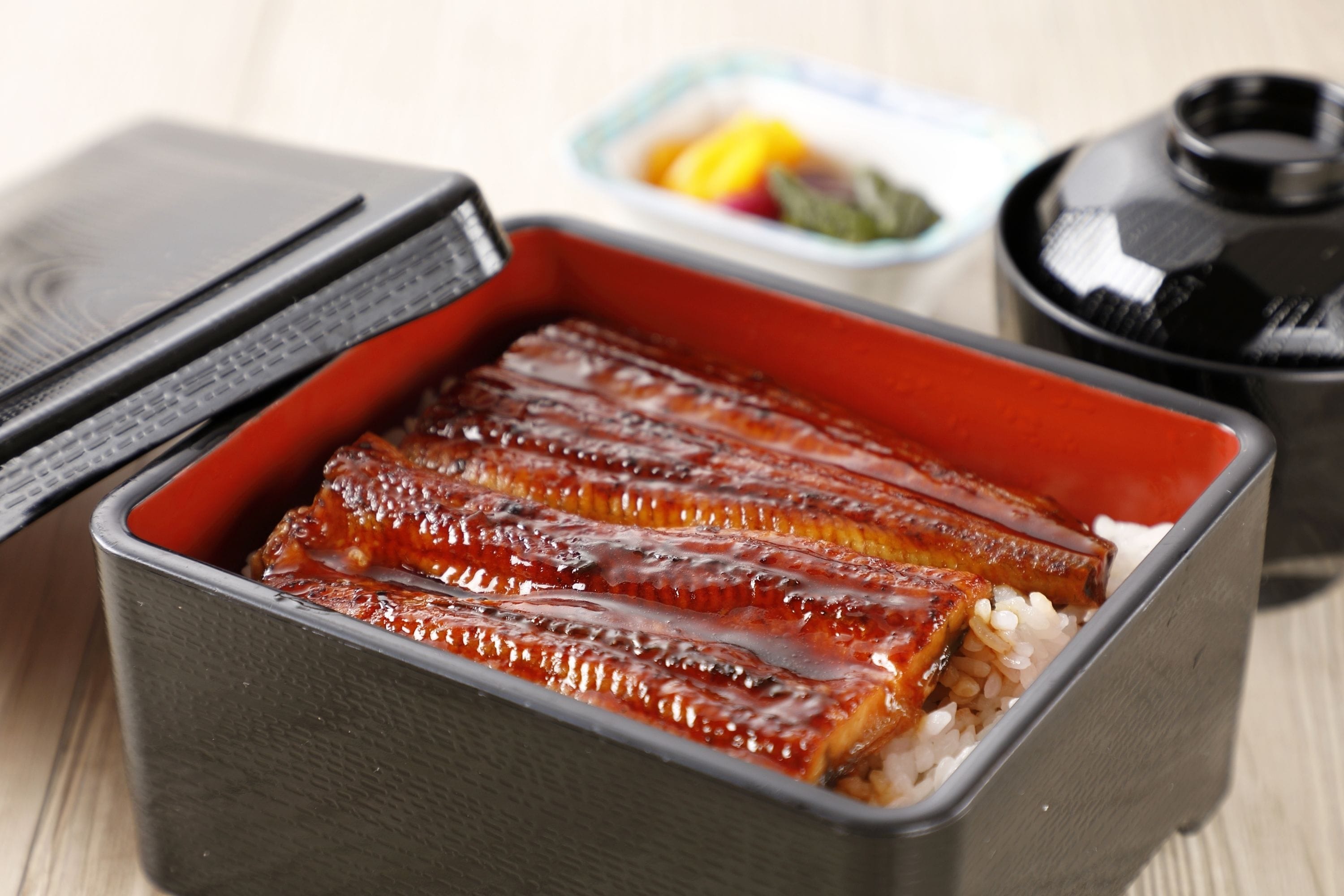 A container with grilled fish and rice.