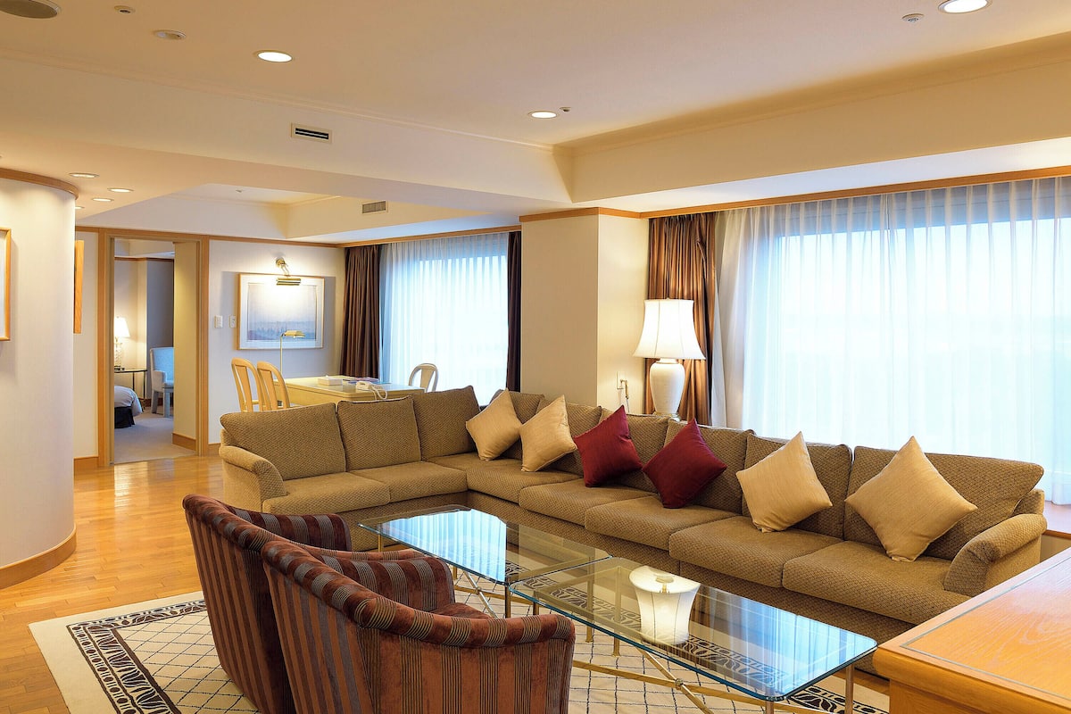 A modern living room with a sectional sofa, a glass coffee table, and a dining area with a table and chairs.