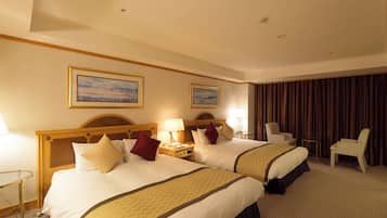 A hotel room with two beds, a desk, and a chair.