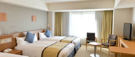 A hotel room with two beds, a desk, a chair, a television, and a window with curtains.