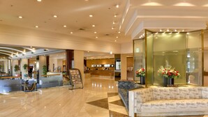 Un hall de hotel con mostrador de recepción, un sofá y una mampara de vidrio.