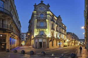 Un hotel elegante con un cartel llamativo, ventanas amplias y una fachada bien iluminada.