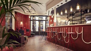 A bar area with red chairs, a counter, and a wine display. - Grand Hôtel du Midi Montpellier - Opéra Comédie (Montpellier)