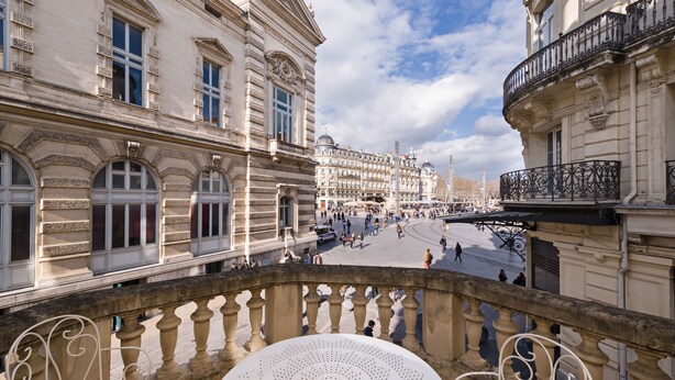 A balcony with ornate balustrades overlooking a public square with historic buildings. - Grand Hôtel du Midi Montpellier - Opéra Comédie (Montpellier)