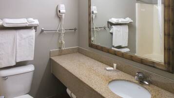A bathroom with a toilet, sink, and two hair dryers mounted on the wall.