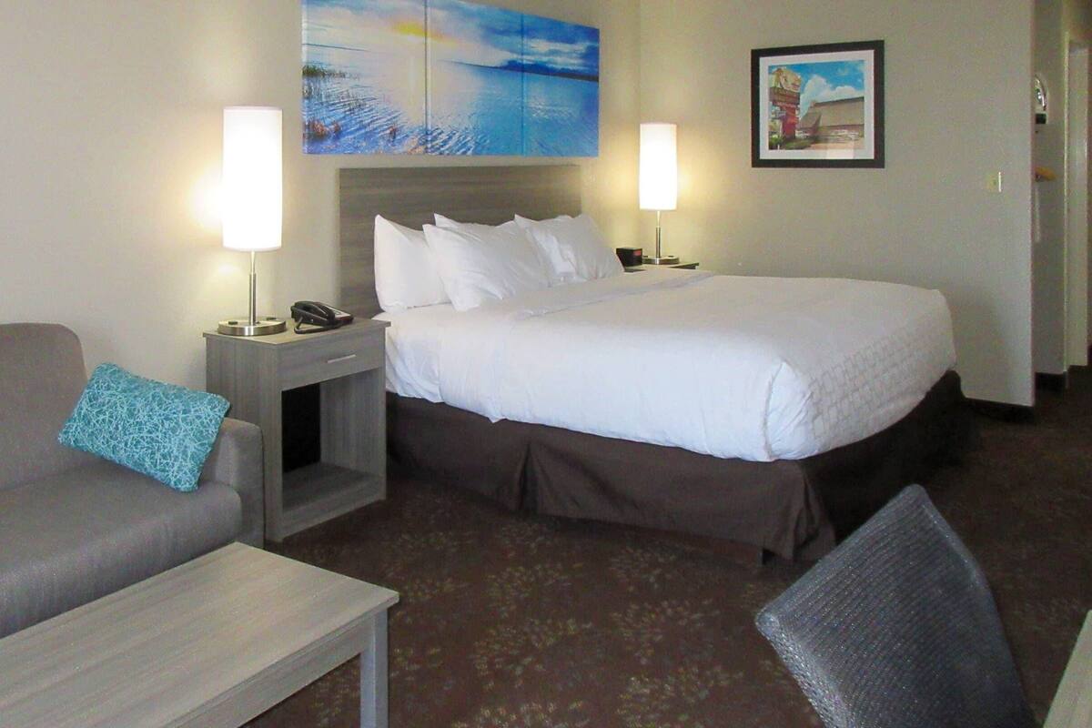A hotel room with a bed, a sofa, a nightstand, and a small table.