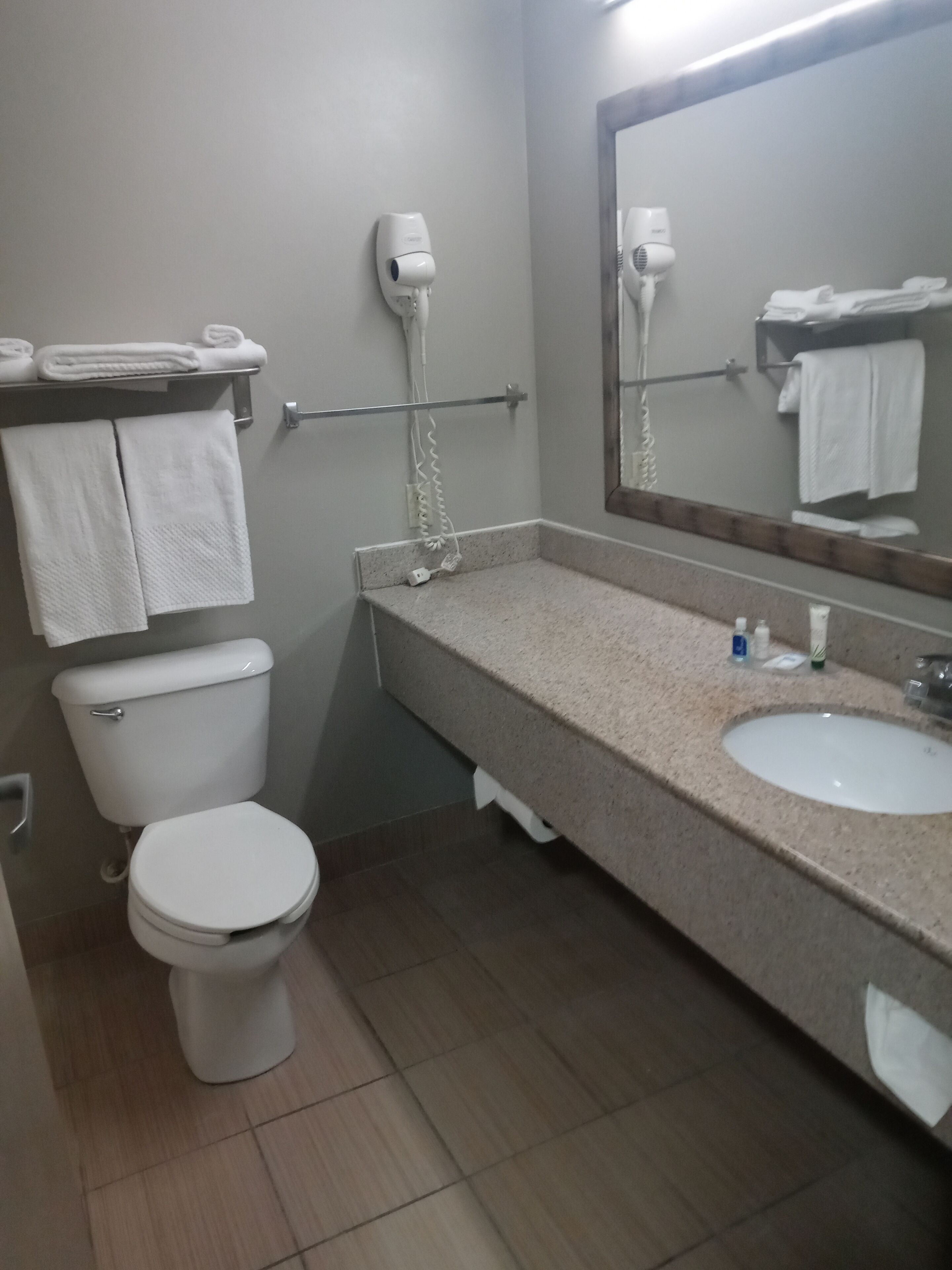 A bathroom with a toilet, sink, and hairdryer on the wall.